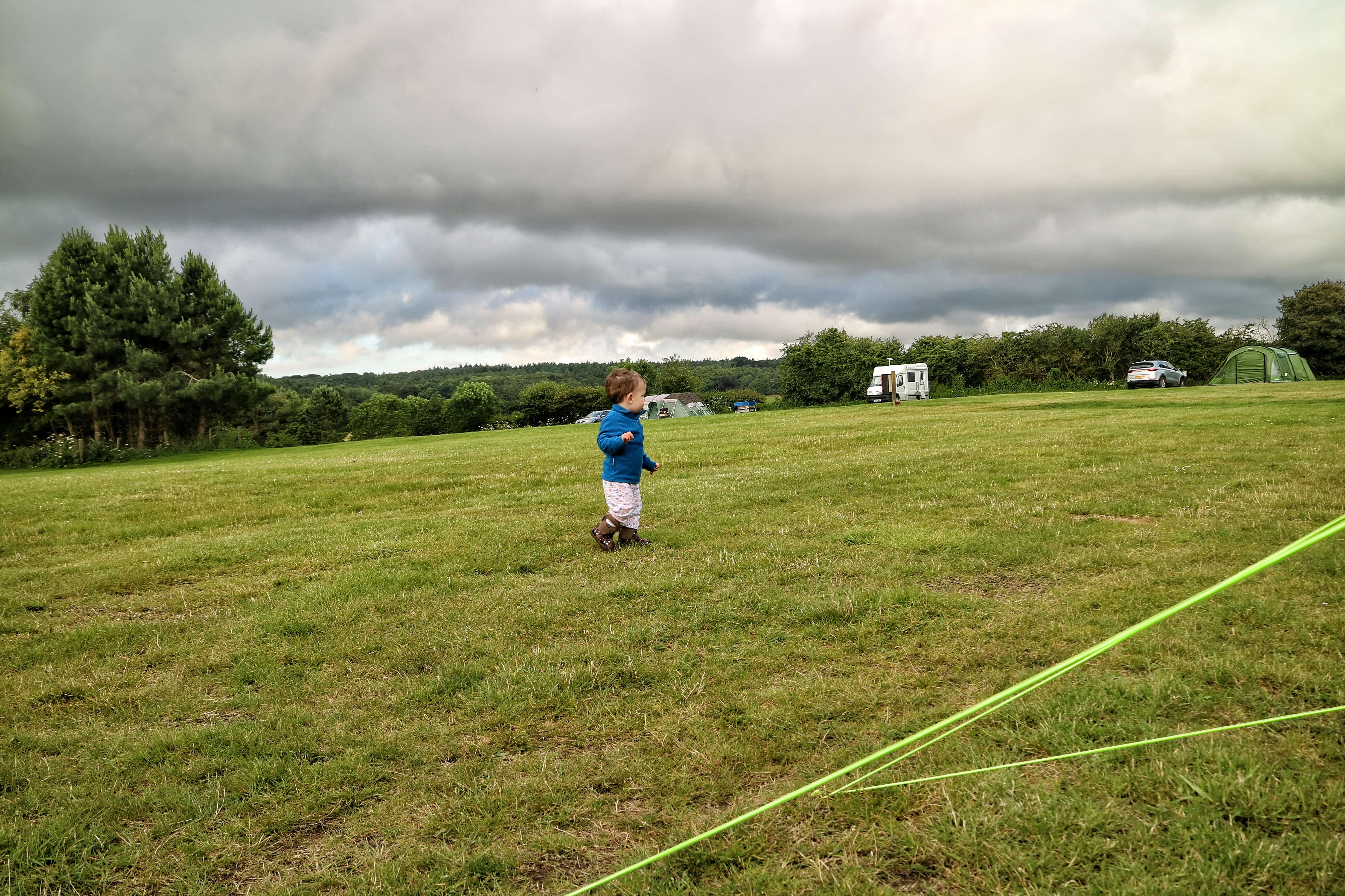 A toddler runs around a campsite